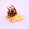 Mini pince à cheveux papillon jaune translucide avec pince écaille de tortue.