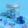 Pot transparent avec couvercle métal contenant mix perles Frozen bleues, blanches et roses en plastique et acrylique.
