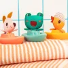 Trois bateaux flottants colorés avec personnages animaux en tissu, sur serviettes rayées.