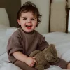Enfant souriant en pyjama beige tenant peluche lumineuse Lou ours marron doux