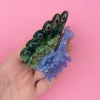 Pince à cheveux Paon Coucou Suzette en acrylique vert et bleu nacré, motifs plume et tête de paon.