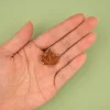 Pin's feuille d'érable orange pailleté avec contour doré, posé sur une main.