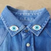 Pin's Oeil Coucou Suzette, deux yeux bleus et blancs avec cils dorés sur col jean.