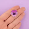 Pin's en métal doré représentant une fleur pensée mauve aux pétales roses et violets.