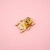 Pin's en métal doré en forme de scarabée avec fermoir papillon, fond rose.