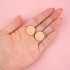 Deux pin's seins blancs ronds avec aréoles roses, posés sur une main ouverte.