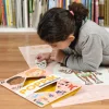 Enfant posée au sol, jouant avec stickers squelette sur poster Le corps humain Poppik.