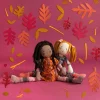 Poupée Violette Les Rosalies assise robe orange motifs floraux fond rose feuilles décoratives rouges et jaunes