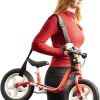 Femme portant une draisienne rouge avec sangle de transport BUDDY noire Puky.
