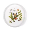 Assiette en porcelaine blanche avec lapin habillé orange et fleurs décoratives vertes.