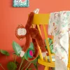 Singe en peluche marron suspendu à une chaise jaune avec feuille et pastèque en tissu