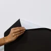Main féminine posant un coin du tableau magnétique Ma ville Ferflex noir autocollant.
