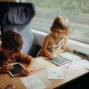 Deux enfants assis dans un train dessinant sur tablettes Kidydraw-mini avec des dessins d’animaux.