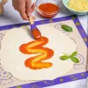 Tapis de cuisson Chefclub Kids violet avec pâte à pizza et sauce tomate étalée