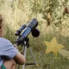 Télescope astronomique Kidytélescope bleu Kidywolf sur trépied argenté dans herbe sèche