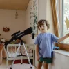 Télescope Kidytélescope noir sur trépied argenté avec enfant en t-shirt bleu.