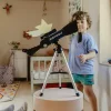 Télescope astronomique Kidytélescope bleu et noir sur trépied blanc avec enfant jouant.