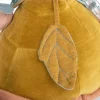 Détail feuille en tissu jaune moutarde cousue sur tortue d'activités en velours Moulin Roty