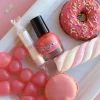 Vernis à ongles corail Rosajou sur plateau avec bonbons roses et donut coloré